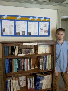 young man standing next to bookcase and Revolution 250 timeline.